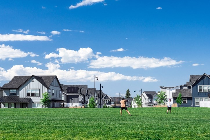 Two people play frisbee in Reed’s Crossing Park under a brilliant blue sky.