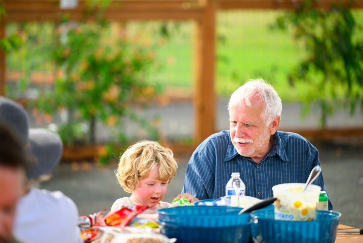 A child and grandfather enjoy a barbeque in Reed’s Crossing Park.