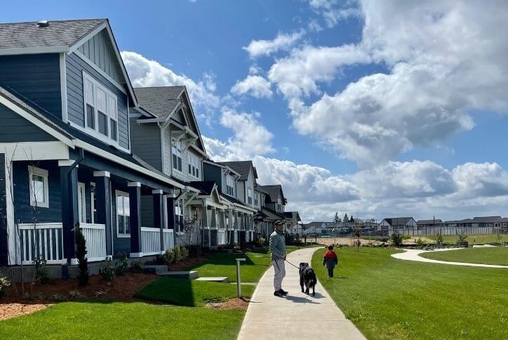 A man, child, and dog walk past homes at Reed’s Crossing in Hillsboro, Oregon.