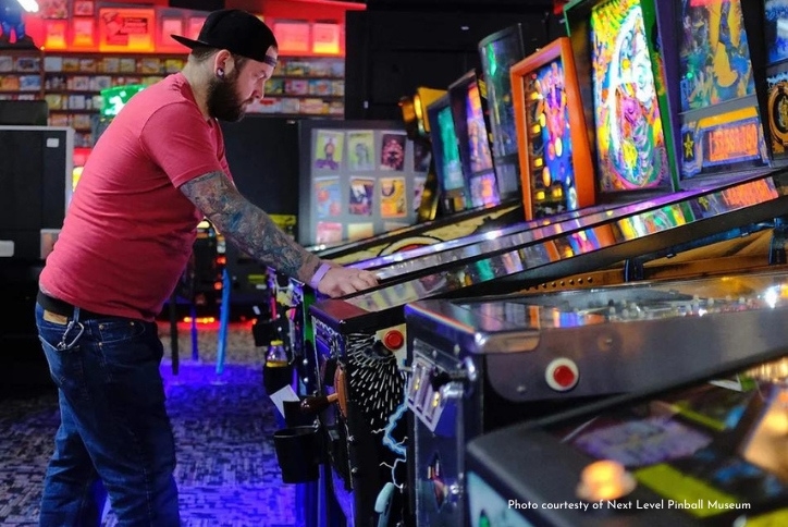 A tattooed man plays pinball at Hillsboro’s Next Level Pinball Museum.