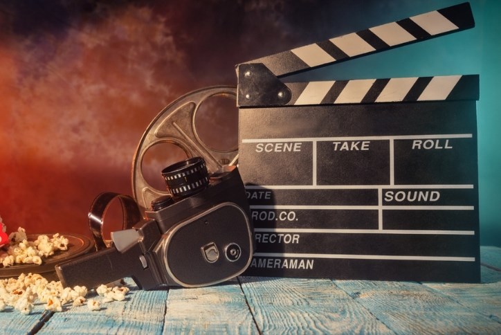 A group of film-related items including a camera, a blank film slate, a roll of film, and popcorn.