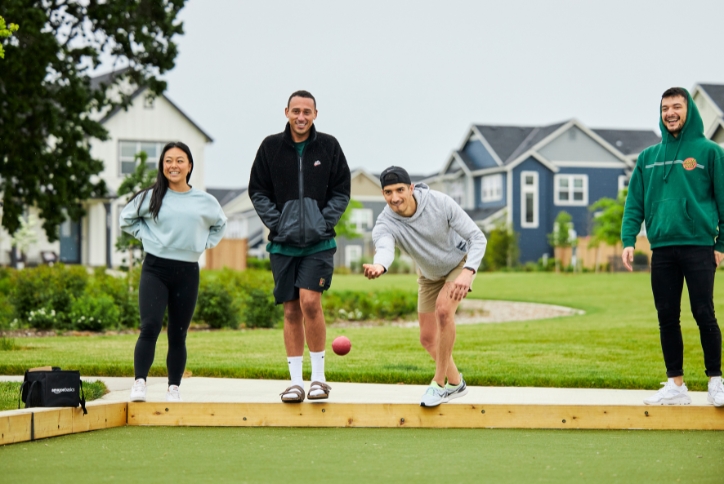 Four young adults play bocce ball at Tamarack Park in Hillsboro, Oregon.