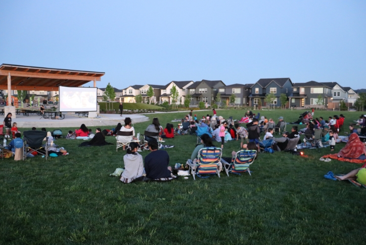 A group of people watch a movie at dusk in Reed’s Crossing Park.