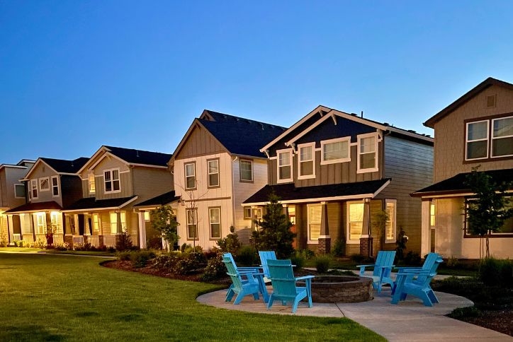 A community firepit at Reed’s Crossing at dusk, with warmly lit homes in the background.