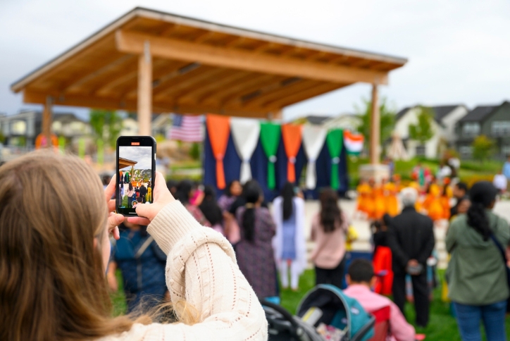 A woman holds up her phone to take a photo at an event in Reed’s Crossing Park.