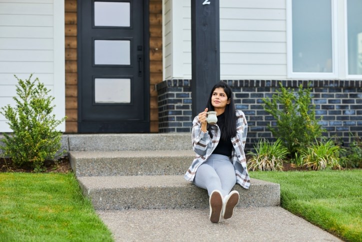 A woman sits in front of a home in South Hillsboro’s Reed’s Crossing neighborhood.