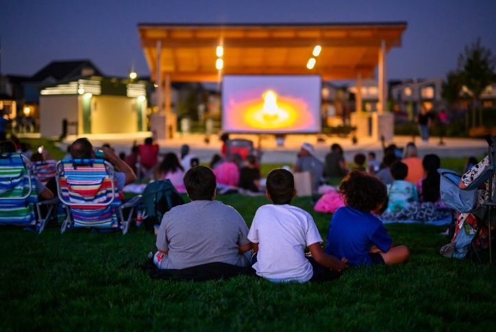 People come together at dusk to enjoy a movie in Reed’s Crossing Park.