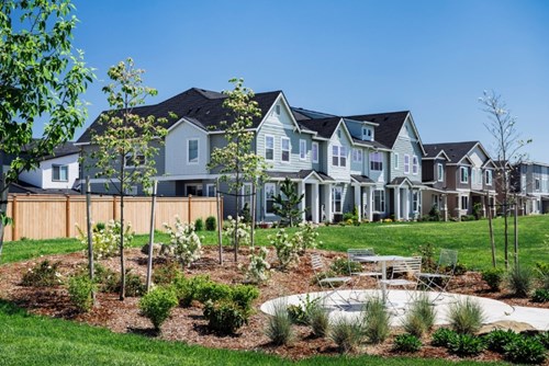 A landscaped area and café table sit near new homes for sale in Reed’s Crossing.