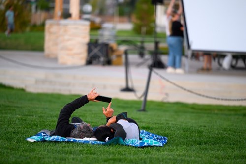 A couple reclines on a blanket in the grass at movie night in Reed’s Crossing Park.