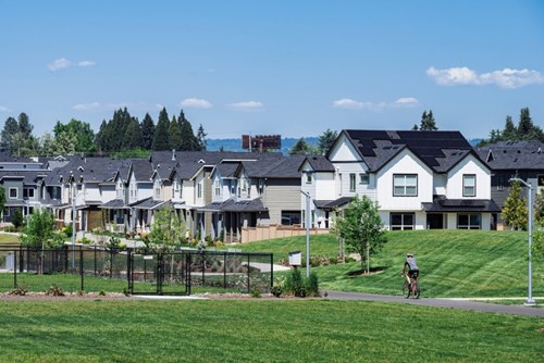 A man rides a bicycle in front of a home with solar panels in South Hillsboro.