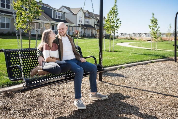  A couple smiles at each other while sitting on a bench swing in Hillsboro’s Tamarack Park.