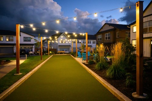 A shared bocce ball and firepit area lit with warm string lights in Reed’s Crossing.