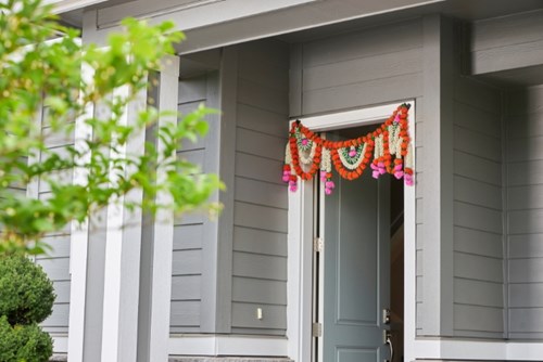 A brightly colored garland hangs over the door of a home, welcoming visitors.